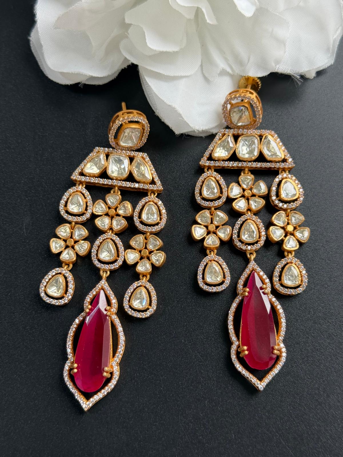 Ornate earrings with red stones on a dark background