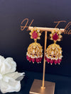 Gold and red earrings on a stand with a dark background
