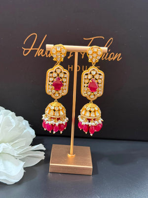 Gold and red earrings on a gold stand with a black background